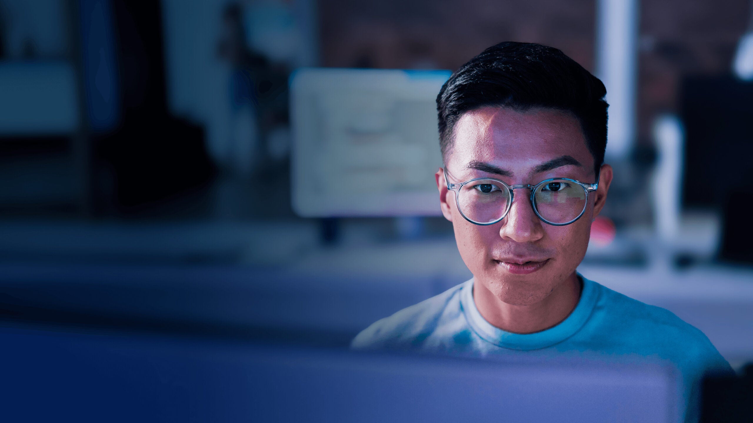 Man with glasses looking at monitor on desk