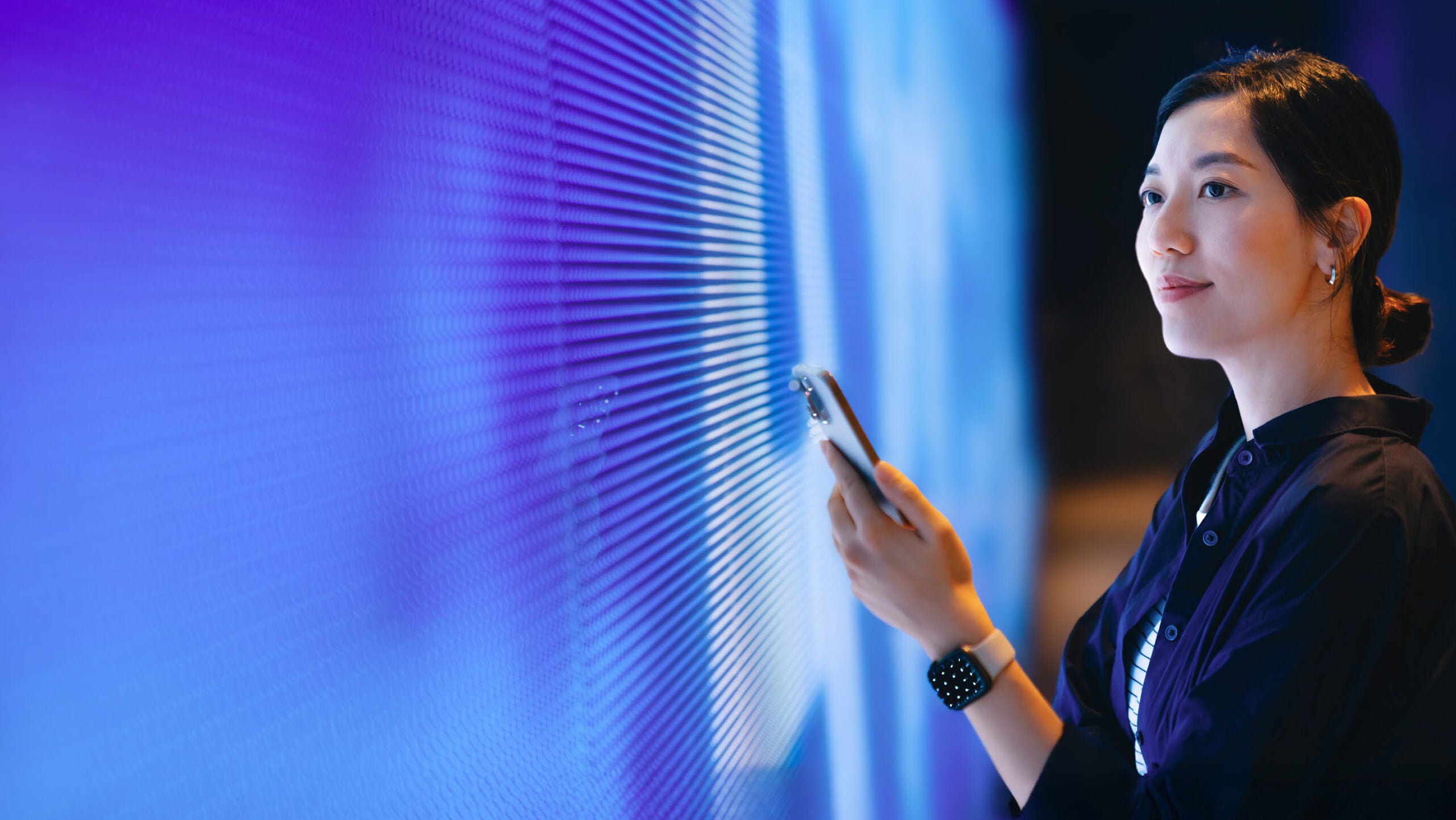 woman with phone gazing through office window shades