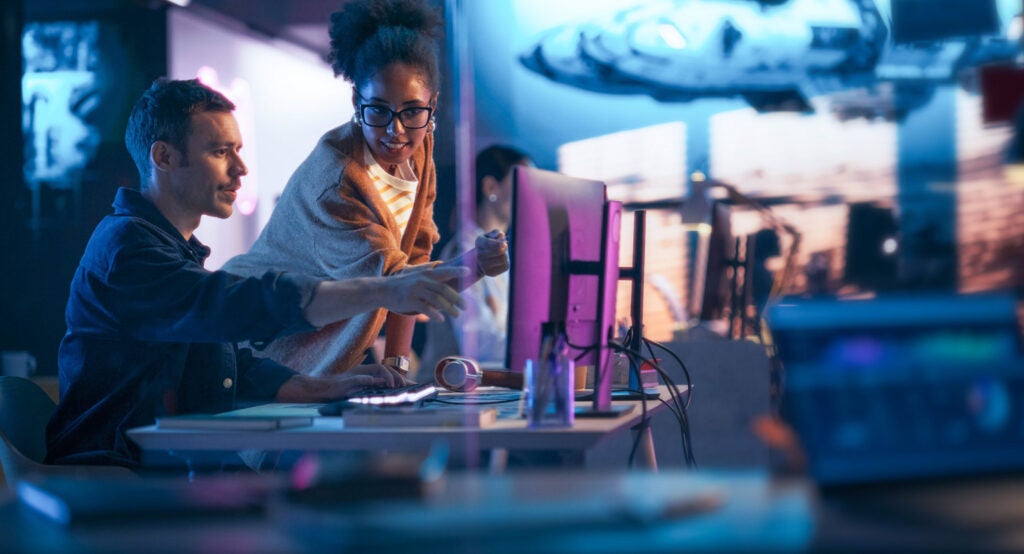 Coworkers pointing to monitor in office