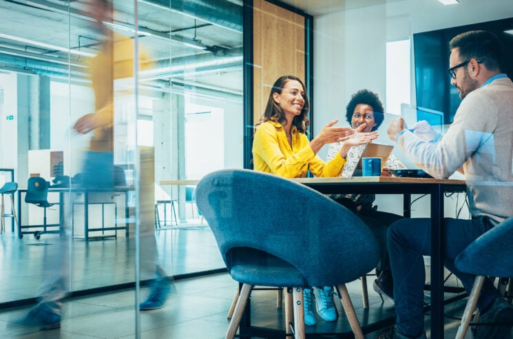 Man and two women sitting in conference room