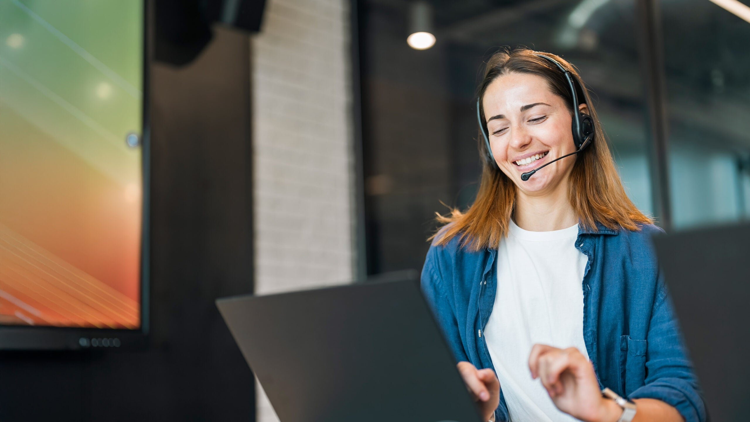 Woman with headset on laptop